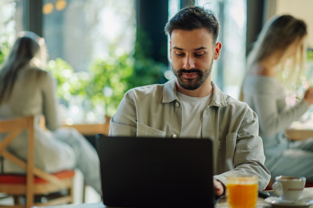 Focused freelancer working on laptop in cafe, enjoying a refreshing break