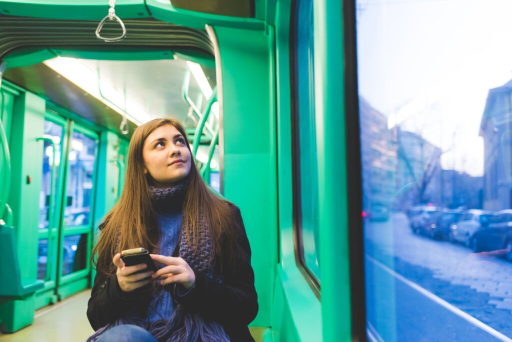 young woman outdoor using smart phone travelling transport