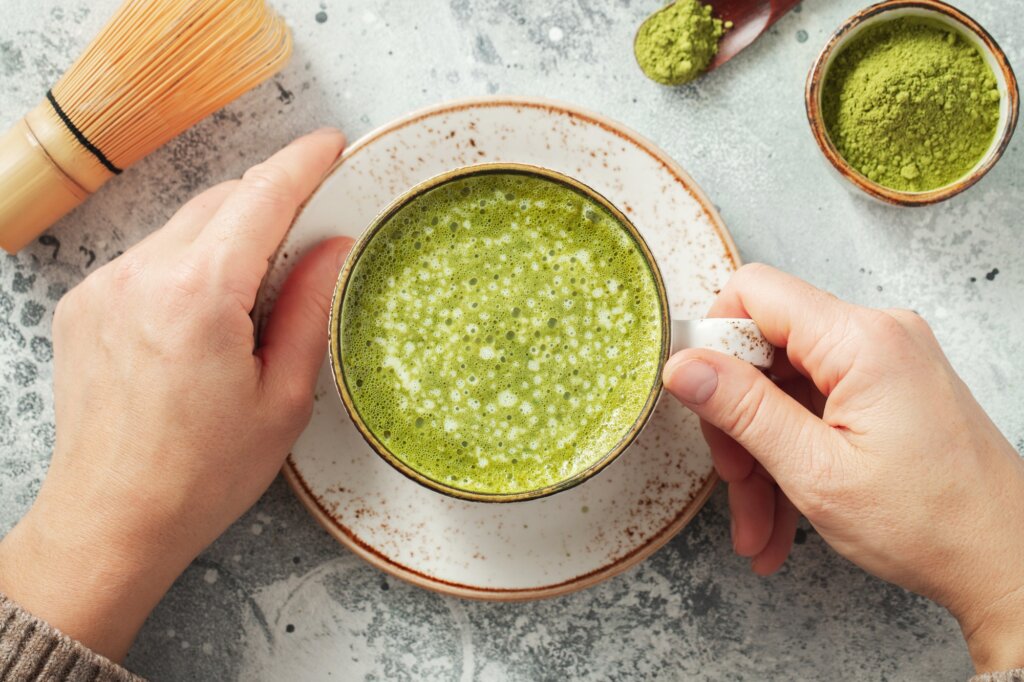 Cup of Matcha Green Tea in woman hands. Top view. flat lay